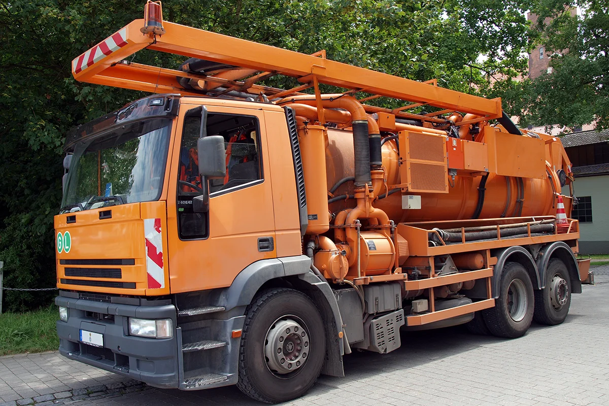 Eures • Oranger Saugfahrzeug für Abfallentsorgung auf Straße.