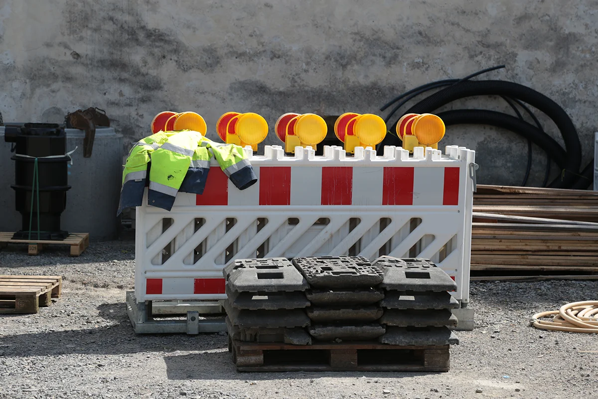 eures-baustelle-absperrungen Eures • Baustelle mit Absperrung, Warnleuchten und reflektierender Arbeitskleidung.