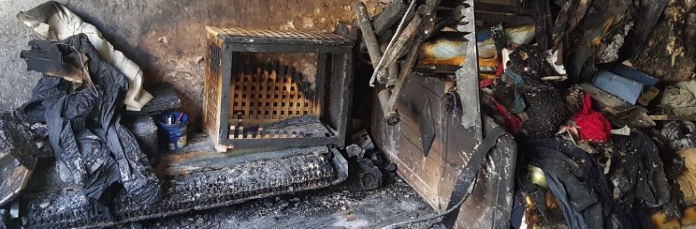 brand-wasserschaden-1 Eures • Zerstörte Wohnung nach Brand; verkohlte Möbel und Kleidungsstücke sichtbar.