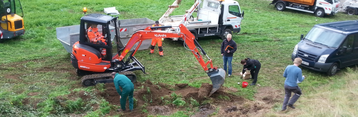 eures-unfallstellensanierung-1 Eures • Baggerarbeiten auf einer Wiese mit mehreren anwesenden Personen.